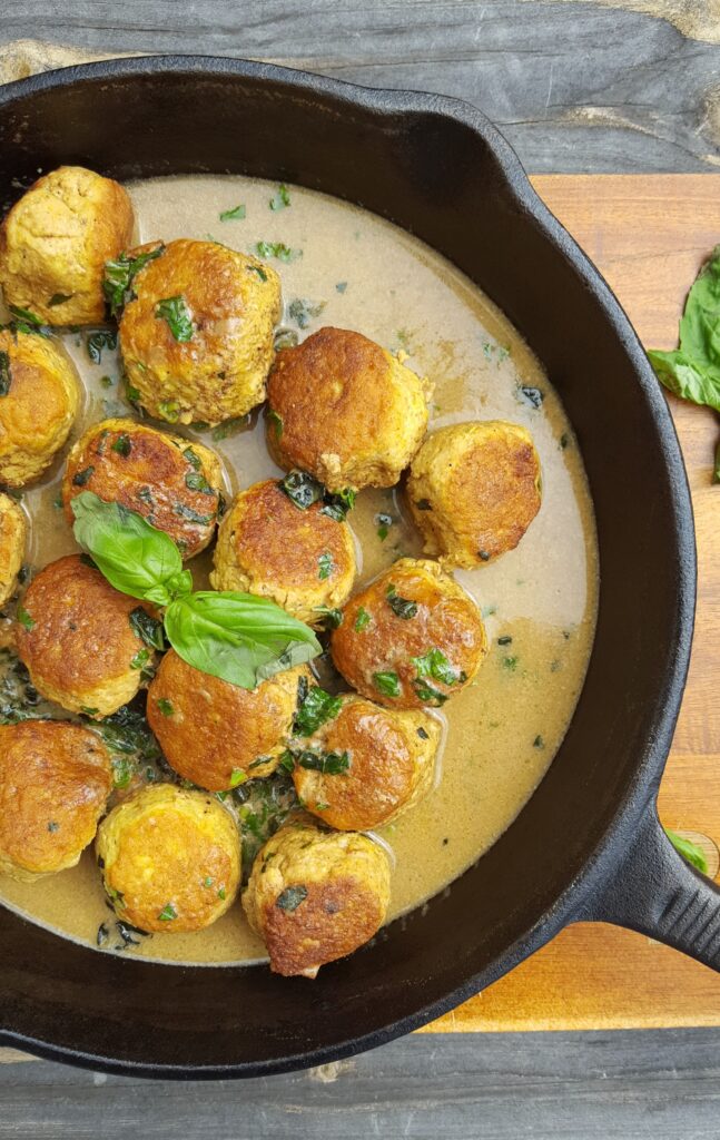 Delicious Paleo Curry Chicken Meatballs are served in a flavorful broth and garnished with fresh basil.