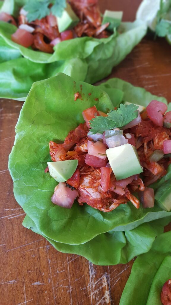 Vegan jackfruit is flavored with plenty of spices and transformed into carnitas, wrapped in lettuce leaves and garnished with traditional taco toppings.