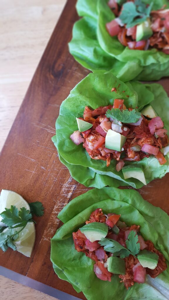 These lettuce-wrapped carnitas are served Vegan style! Spicy jackfruit is wrapped in butter lettuce leaves and garnished with plenty of traditional taco toppings.