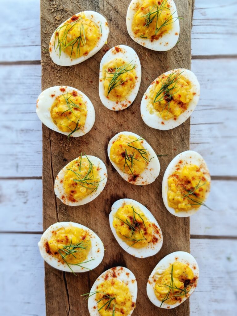 Each egg white half is filled with a gluten-free, dairy-free egg yolk mixture and garnished with a few sprigs of fennel fronds and a sprinkling of paprika.