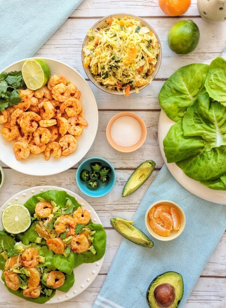 An overlay style photo displays a shrimp taco bar comprised of blackened shrimp, spicy citrus cilantro coleslaw, bibb lettuce, avocado, jalapenos and limes. Two assembled blackened shrimp lettuce wraps are also displayed.