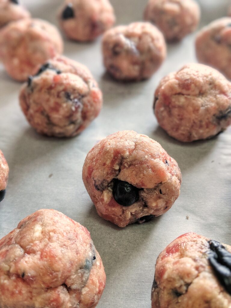The grain-free, gluten-free and dairy-free mixture used to make these Paleo Baked Blueberry Pancakes & Sausage Balls is rounded into equally-sized meatballs and baked until golden brown.