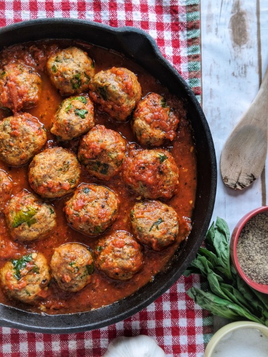 Light and fluffy Baked Italian Meatballs are reheated in a cast iron skillet with vibrant red homemade marinara sauce. 