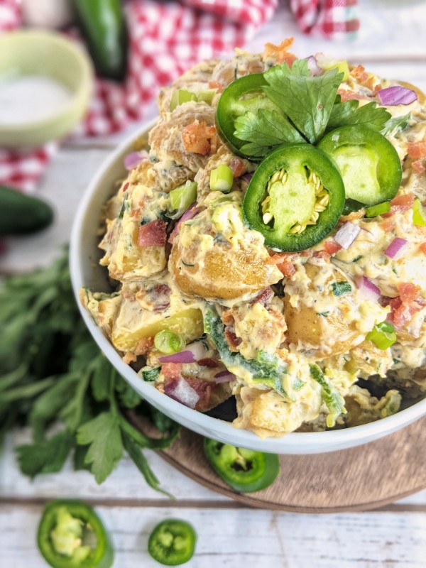 Roasted baby gold potatoes are dressed with a creamy dairy-free sauce, red and green onions, bacon and jalapenos. 