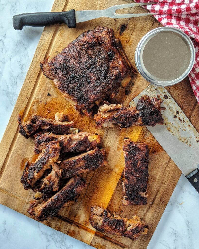 A rack of juicy, fall-off-the-bone Memphis-style sugar-free pork ribs are sliced on a cutting board. 