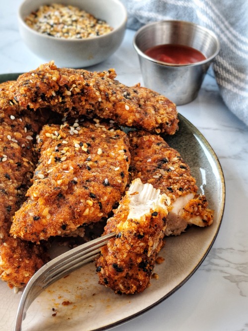 An Everything Bagel Chicken Tender is cut into showing how crispy it is on the outside and juicy it is on the inside by cooking them in an air fryer.