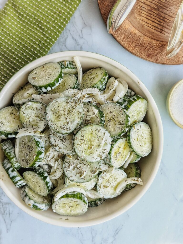 Seedless cucumbers sliced into coins and slivered Vidalia onions are dressed in a creamy dairy-free sauce and presented in a large bowl.