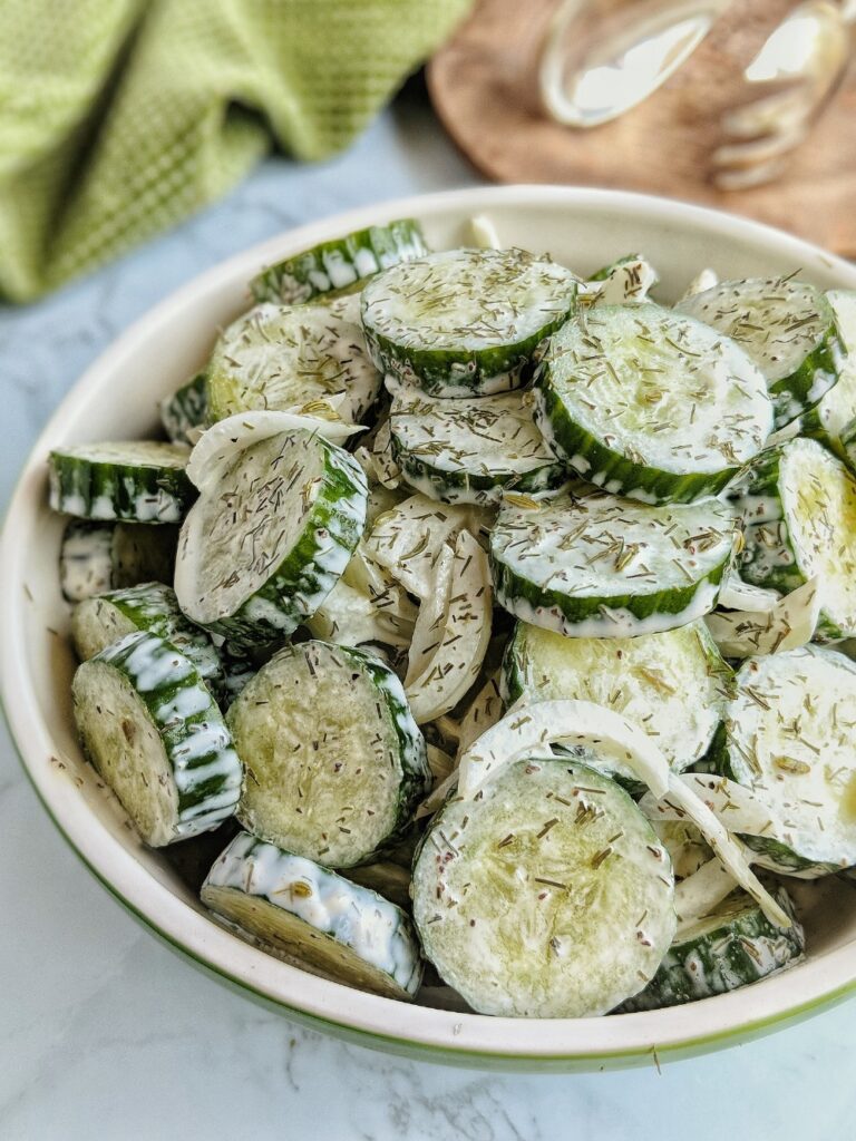 Sugar-free and Keto-friendly Creamy Cucumber Salad is served in a large green bowl.