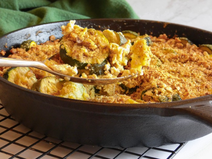 Served from an oven-safe skillet is tender-crisp zucchini in a creamy dairy-free au Gratin style sauce topped with toasted grain-free crackers crumbs.