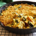 Creamy dairy-free au gratin style zucchini is served fresh from the oven in a large cast iron skillet.
