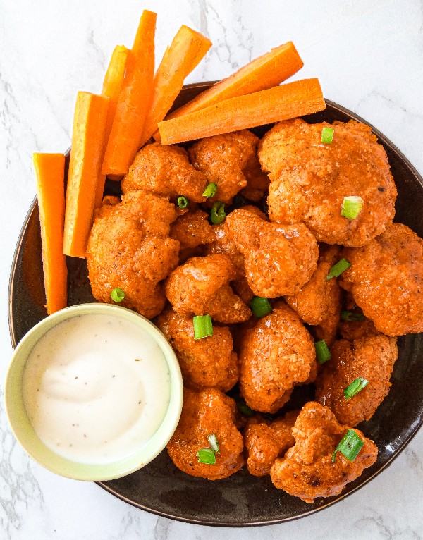 Breaded oven roasted cauliflower are tossed in buffalo sauce and served with fresh carrot sticks and creamy ranch dressing. 